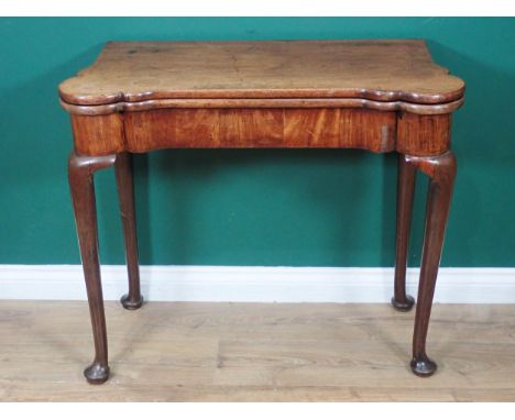 A Georgian mahogany Card Table with shaped fold-over top enclosing baize lining and counter wells, raised on slender cabriole