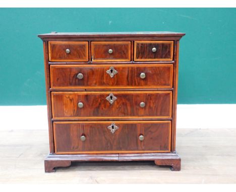 A George III walnut veneered and crossbanded apprentice piece Chest of three short and three long drawers mounted on ogee bra