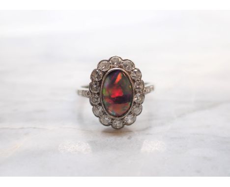 A Black Opal and Diamond Cluster Ring millegrain-set oval opal within a frame of brilliant-cut diamonds, further stones to sh