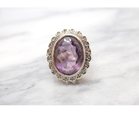 An Amethyst and Diamond Cluster Ring rubover-set oval-cut amethyst within a frame of illusion-set eight-cut diamonds in 9ct g