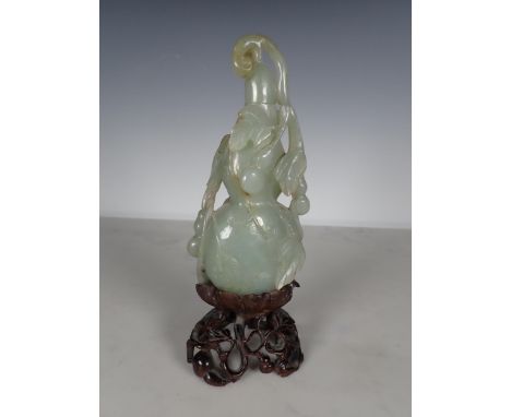 An Oriental carved jade lidded Bottle vase with leafage and fruit decoration, on a carved hardwood stand, 8in H