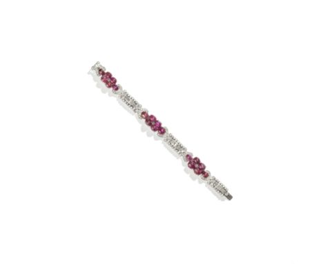 ROOD: RUBY AND DIAMOND BRACELET, CIRCA 1930The articulating openwork links with scroll motifs, set throughout with brilliant 