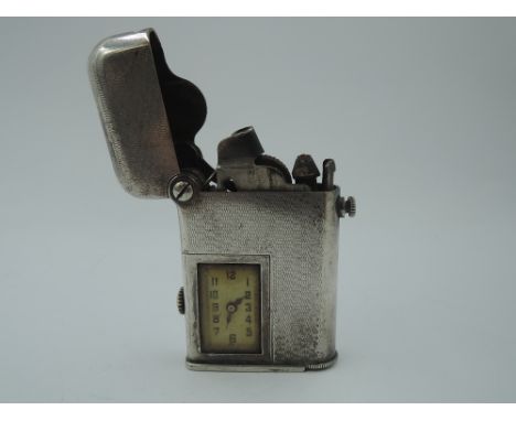 A Swiss white metal 1920's Thorens Brevete lighter no:81816 having engine turned decoration to body with inset watch face
Con