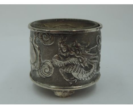 An early 20th Century Chinese silver salt having repousse dancing dragon decoration with plain cartouche, plain glass liner a