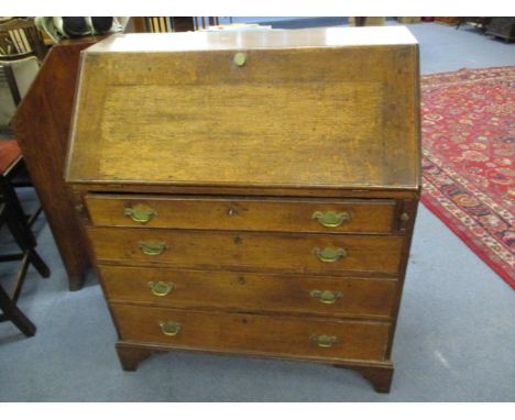 A George III oak bureau, the fall flap enclosing a central cupboard flanked by short drawers and pigeonholes with four gradua