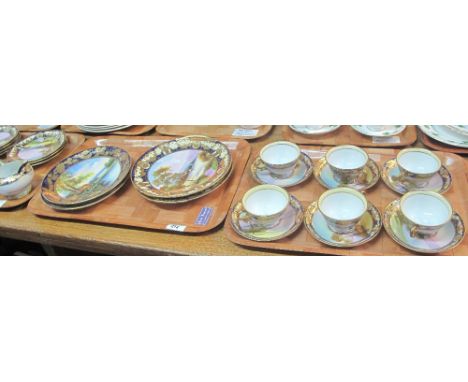 Four trays of Noritake porcelain teaware on a white ground with gilt foliate and landscape decoration, comprising: cups and s