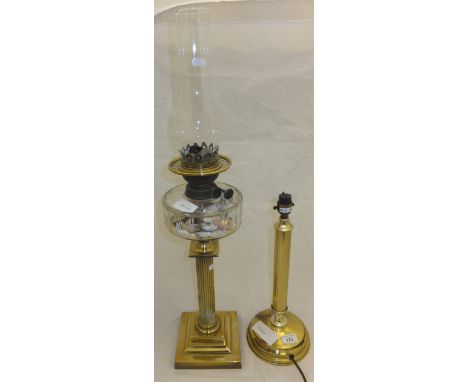 A brass bodied oil lamp, the well filled with shells, together with a modern brass bodied table lamp