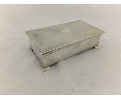 A George V silver cased cigarette box with engine turned decoration to top and raised on four bracket feet (by Baker Brothers