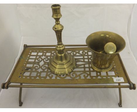A brass pestle and mortar, large brass trivet on X framed base and brass candlestick