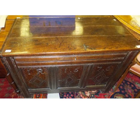 A 17th Century oak coffer, the three plank top with cleated ends over a carved three panel front with lozenge medallions, ins