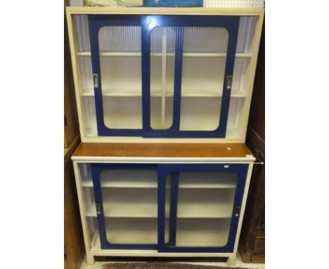 A 1950's painted plywood shelf unit with sliding glazed doors, and another similar