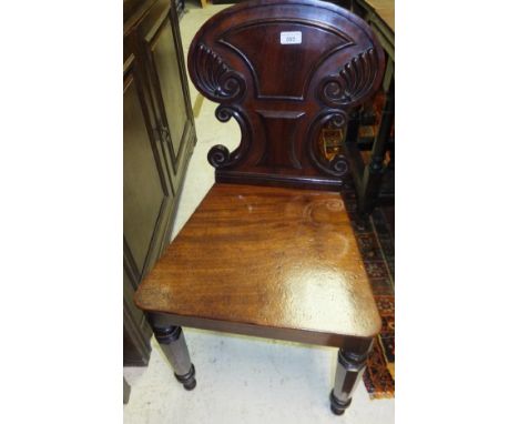 An early 19th Century mahogany panel seated hall chair with C-scroll and cornucopia carved back, raised on octagonal tapering