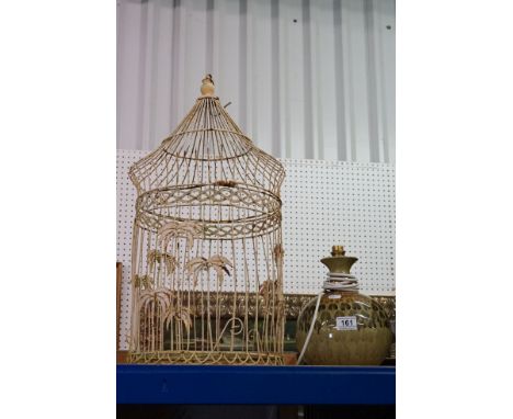 A white hanging bird cage planter together with a ceramic lamp base. 