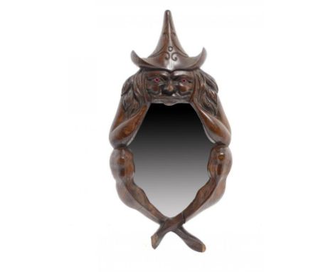 A VICTORIAN CARVED OAK MIRROR IN THE FORM OF A WITCH, LATE 19TH C with red glass eyes, the backboard with inscription "Carved