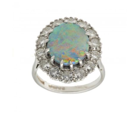 AN OPAL AND DIAMOND CLUSTER RING the opal with a surround of fourteen evenly sized round brilliant cut diamonds, in 18ct whit