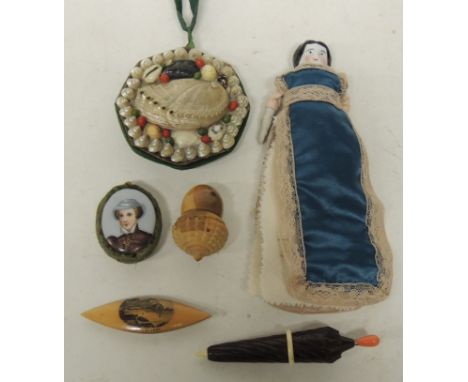 A Mauchlinware tatting shuttle with "Ilfracombe" image; a German porcelain doll needle holder; a carved wood umbrella needle 