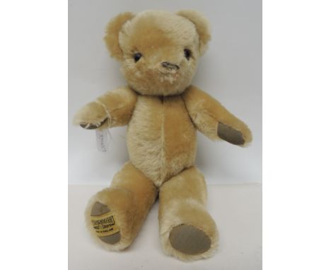 A Merrythought teddy bear with golden plush, plastic eyes, stitched nose and fabric pads, labelled to base of one foot, 33cms