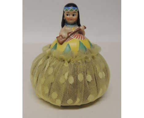 A c.1930's ceramic half doll lavender bag, the doll modelled as a North American Indian girl holding a rifle and with net bag