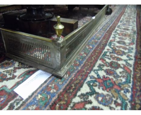 An Early 20th Century Brass and Steel Fender with pierced decoration, standing on pad feet.