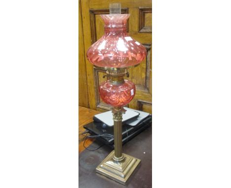 A cranberry glass table lamp and a mahogany cake stand  