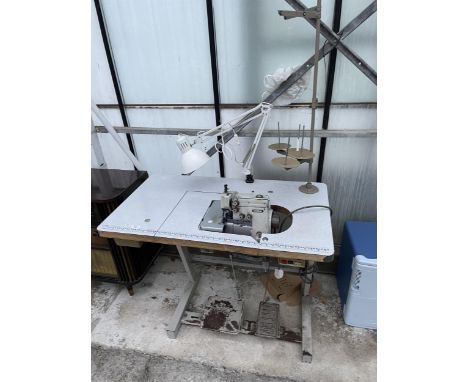 A BROTHER INDUSTRIAL OVERLOCKER SEWING MACHINE WITH TREADLE BASE AND ANGLE POISE LAMP 