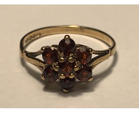 A 9 CARAT GOLD RING WITH SEVEN GARNETS IN A FLOWER DESIGN SIZE M 
