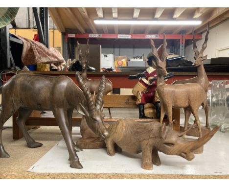 A COLLECTION OF CARVED WOODEN ANIMALS TO INCLUDE ANTELOPES, A RHINOCEROUS, ETC, A BOOK SHELF WITH AND A WOODEN MAN ON A BARRE