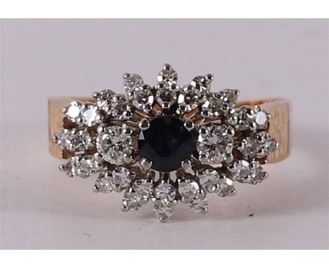 A 14 kt 585/1000 gold cluster ring with a facet cut blue sapphire. Surrounding it are 34 diamonds of a total of 0.75 crt H-VS