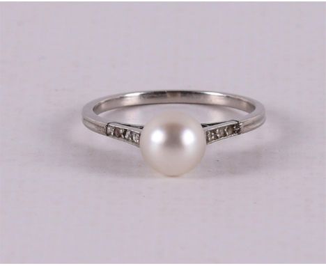 A white gold solitaire ring set with a center pearl and six brilliant cut diamonds on the shoulders of approx. 0.01 crt each,