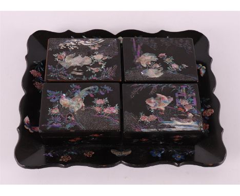 A black lacquer set, consisting of four boxes containing mother-of-pearl chips, on accompanying tray, Japan, around 1900. Mot