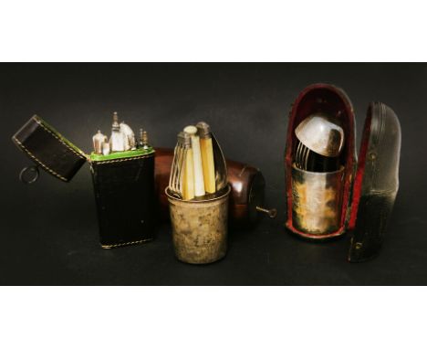 Three travelling cutlery sets,comprising: an hinged barrel case, partially fitted with silver beaker, knife, fork and spoon, 