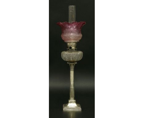 An oil lamp,with etched, tinted cranberry, grille shade, Gardner Duplex burner and cut glass reservoir, on a silver Corinthia