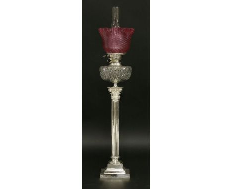 An oil lamp,with a spiral grille cranberry shade, Messenger's burner and cut glass reservoir, on a silver-plated Corinthian c