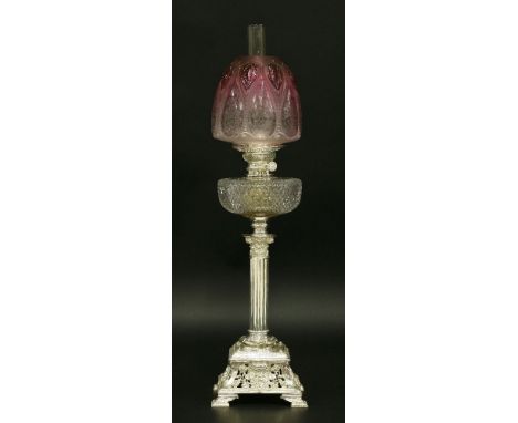 An oil lamp,with etched, moulded and tinted cranberry shade and cut glass reservoir, on a Corinthian column and square mask b