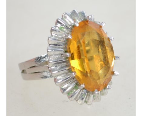 A large silver 1970s citrine cocktail ring having a large raised faceted citrine stone in a prong setting with silver surroun