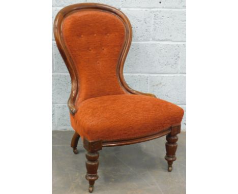 A Victorian mahogany nursing chair, with a padded back and seat, on turned legs with ceramic castors.