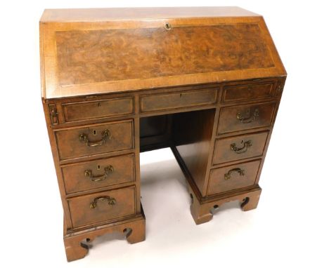 A walnut and figured walnut kneehole bureau, the fall enclosing a fitted interior with a well above an arrangement of six dra