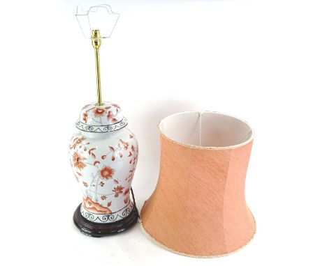 A modern Chinese lamp base, decorated in iron red with flowers etc., with a coral coloured shade, 84cm high.