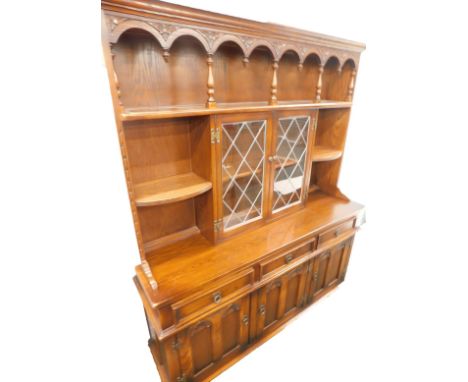 An Old Charm style oak dresser, the raised back with a plate shelf, surrounding two leaded glazed doors, the base with three 