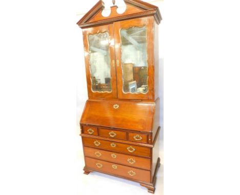 A mid 18thC mahogany bureau bookcase, with broken dentil pediment, centred with a turned urn, above two parcel gilt mirrored 