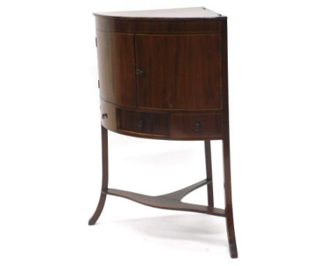 An early 19thC mahogany corner washstand, the top with a hinged lid enclosing  recesses for a bowl, beakers, etc., the front 