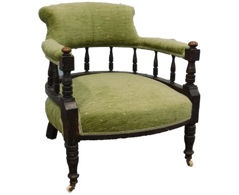 An Edwardian mahogany tub shaped chair, upholstered in green patterned fabric, on turned legs with ceramic castors.