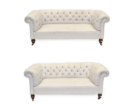 A Pair of Victorian Chesterfield Sofas, late 19th century, recovered in buttoned cream fabric, with overstuffed back support 