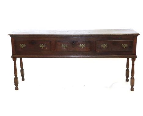 An Early 18th Century Oak Dresser Base, the moulded top above three frieze drawers and moulded apron with turned block legs (