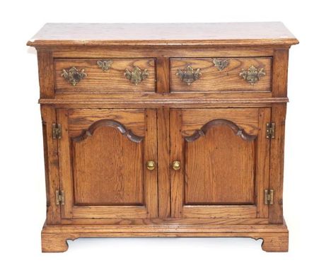 Period Oak Reproductions Ltd: A Small Enclosed Dresser Base, the moulded top above two short drawers and moulded cupboard doo