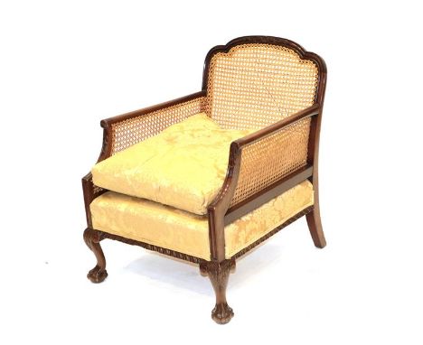 An Early 20th Century Carved Mahogany Single-Cane Bergère, recovered in gold and floral damask, the moulded carved frame with