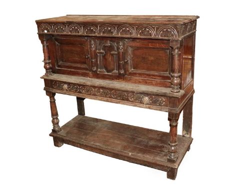A 17th Century Joined Oak Standing Livery Cupboard, the boarded top above a lunette carved frieze and central cupboard door w