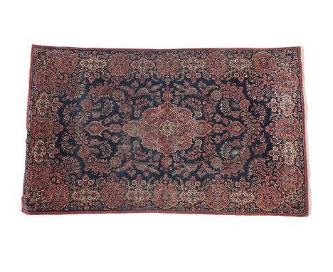 Kashan RugCentral Iran, circa 1930The indigo field of large vines around a terracotta medallion framed by floral borders, 204