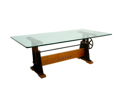 AN INDUSTRIAL GLASS TOPPED HEIGHT ADJUSTABLE DESK The thick rectangular glass top, on two industrial cast iron supports with 