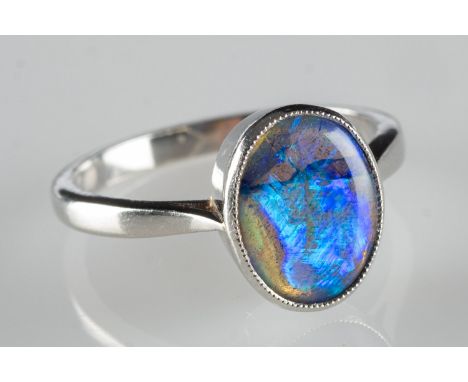 A modern black opal ring, collet set with a black oval opal cabochon, opal measures approx. 10.0mm x 0.8mm, marked Plat, size